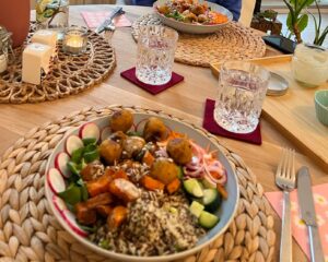 Buddha bowl with falafels, radish, grated carrots, quinoa, cucumber, field salad, sweet potatoes, sunflower seeds, pickled red onions, and creamy dressing